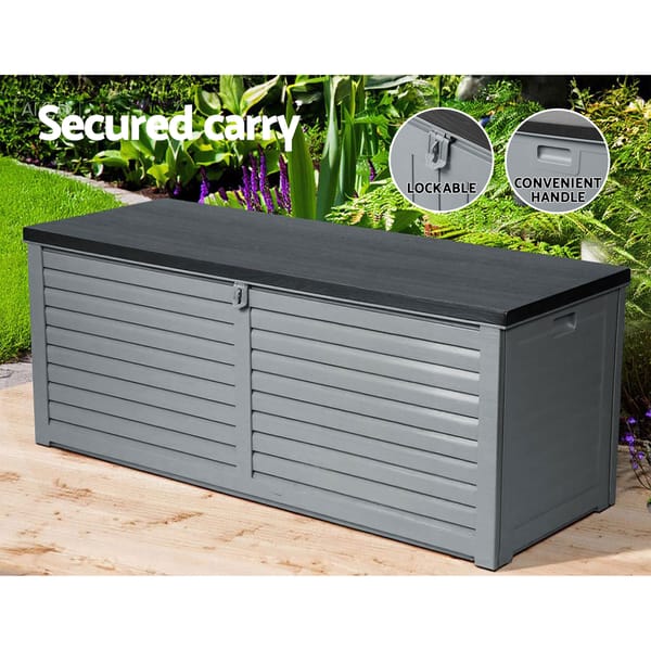 Gray garden storage box with black lid on a wooden surface, surrounded by greenery.