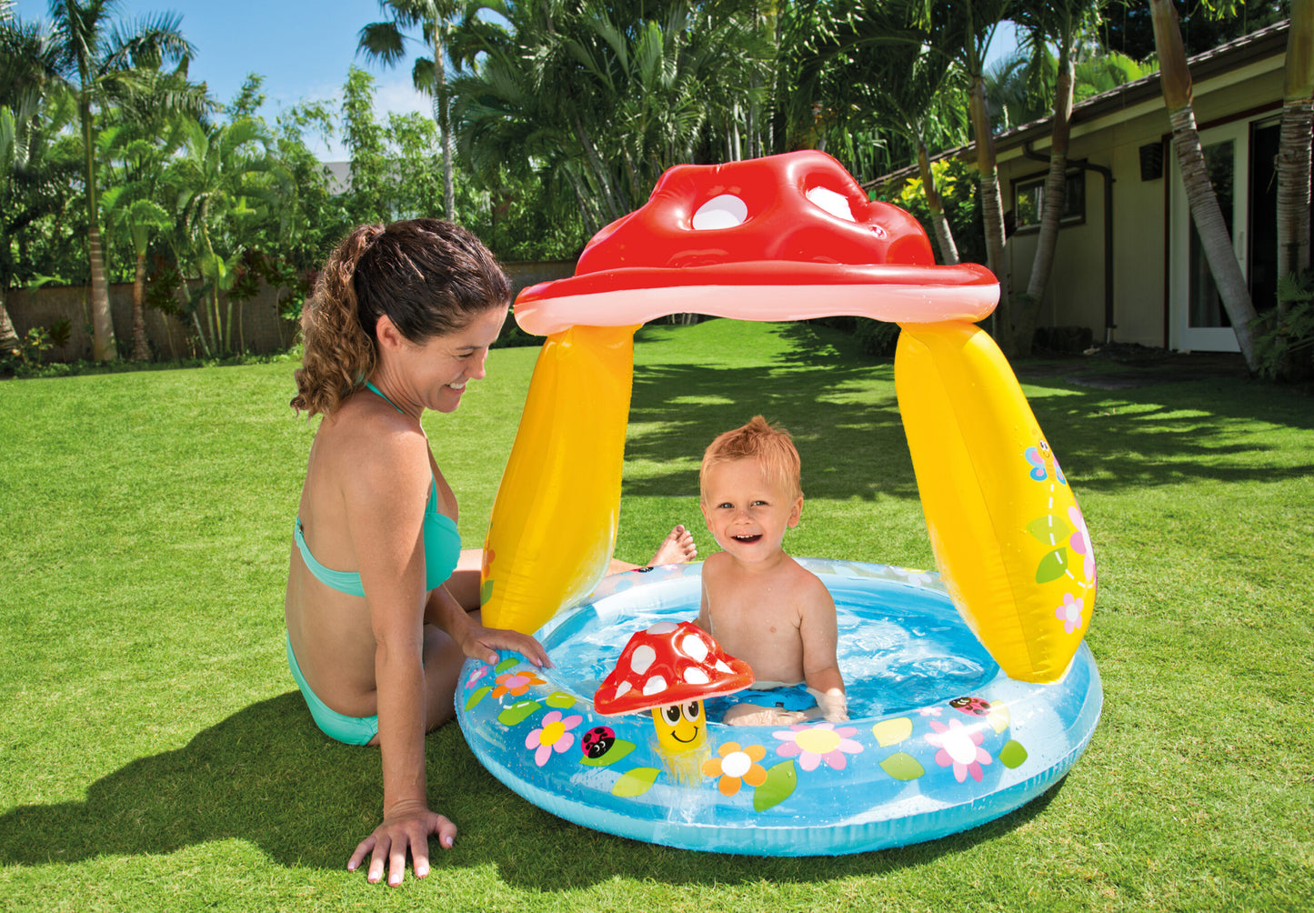 Child playing in a inflatable pool with mushroom design in a garden